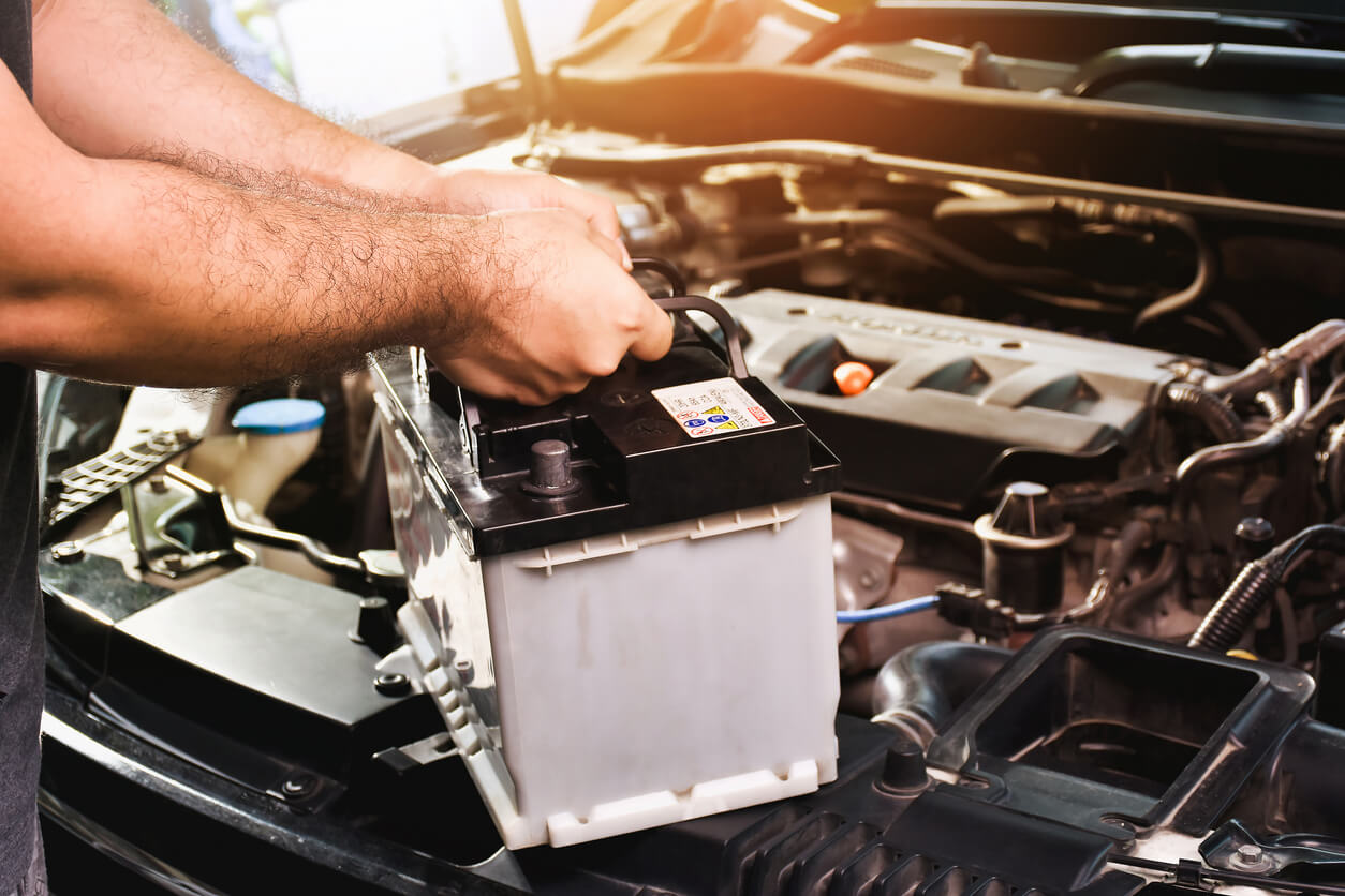 Technician replacing an automotive vehicle battery.