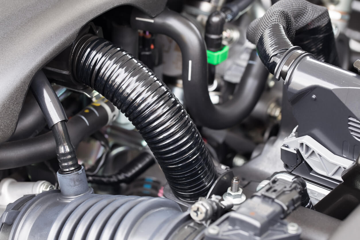 Close up of automotive engine belts and hoses, all newly replaced inside an engine bay.