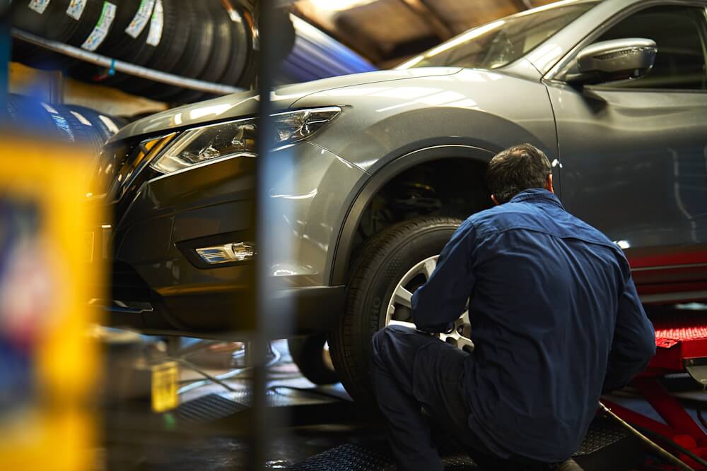 Technician taking a tyre off the side of a raised vehicle.
